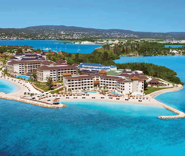 Et feriested ved sjøen med strender og bassenger, omgitt av grøntområder og blått vann. (AI-generert tekst)