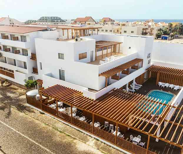 Leilighetsbygg med hvit fasade, tredetaljer og utendørs svømmebasseng. (AI-generert tekst)