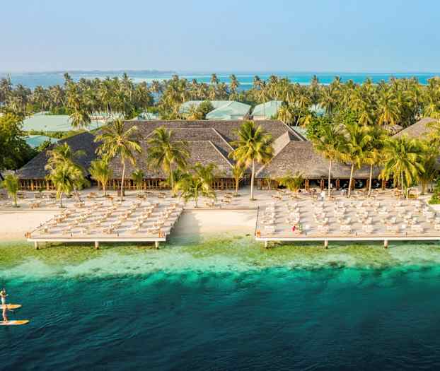 Hotellanlegg ved stranden med solsenger og turkisblått vann. (AI-generert tekst)