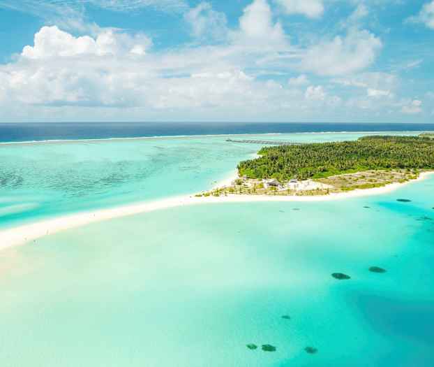 Flyfoto av en tropisk ø omgitt av turkist vann og hvit sandstrand. (AI-generert tekst)