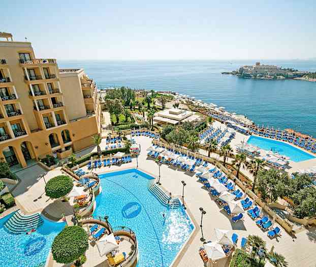 En hotellanlegg med bassenger, solsenger og parasoller, samt havutsikt. (AI-generert tekst)