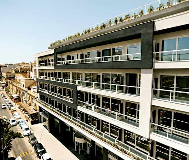 En fleretasjes bygning med moderne balkonger langs fasaden, beliggende ved en bygate. (AI-generert tekst)