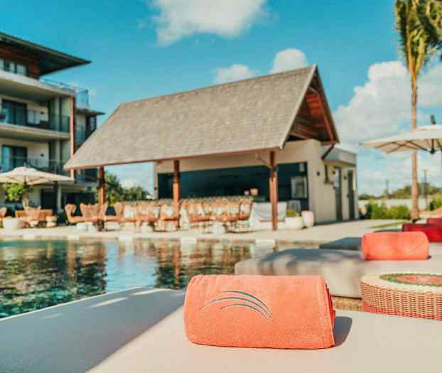 Bassengområde med solsenger og en bygning i bakgrunnen. (AI-generert tekst)