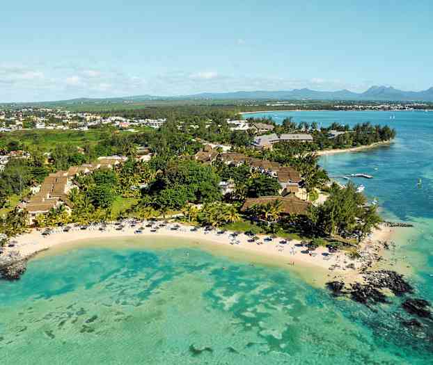 Luftfoto av en tropisk ferieanlegg ved en strand med turkist vann. (AI-generert tekst)