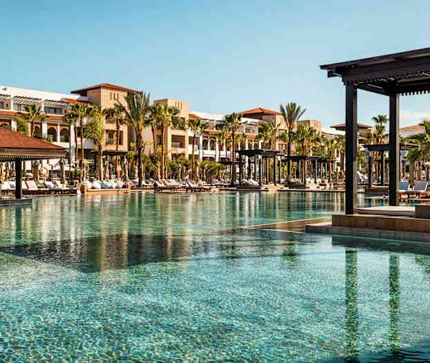 Bassengområde med solsenger og bygninger i bakgrunnen. (AI-generert tekst)