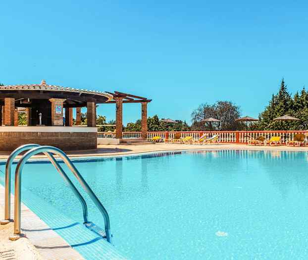 Bassengområde med solsenger, parasoller og en bar ved kanten. (AI-generert tekst)