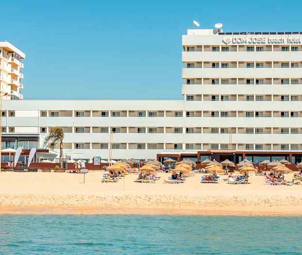 Hotell ved stranden med parasoller og solsenger. (AI-generert tekst)