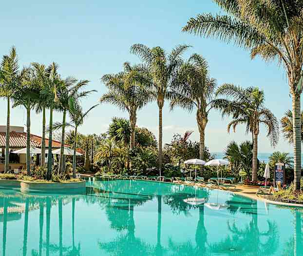 Utendørsbasseng omgitt av palmer og solsenger. (AI-generert tekst)