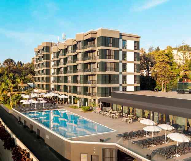 Bilde av et hotell med utendørsbasseng og solsenger, omgitt av trær og vegetasjon. (AI-generert tekst)