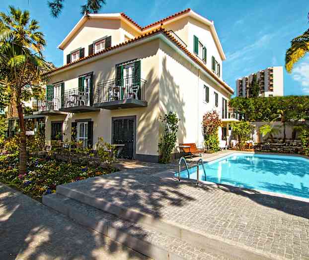 En bygning omgitt av trær med et basseng i forgrunnen. (AI-generert tekst)