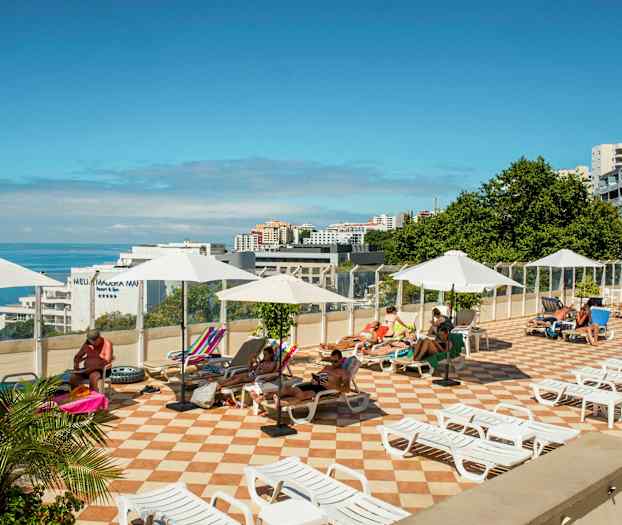 Solterrasse med solsenger og parasoller, med utsikt mot havet. (AI-generert tekst)