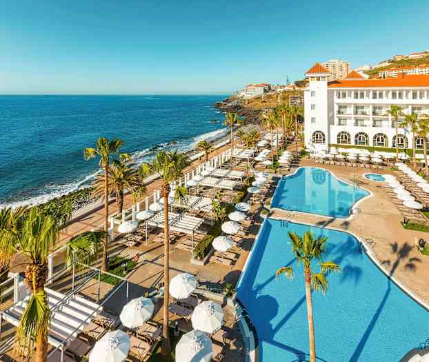 Hotell med bassengområde og utsikt mot havet. (AI-generert tekst)