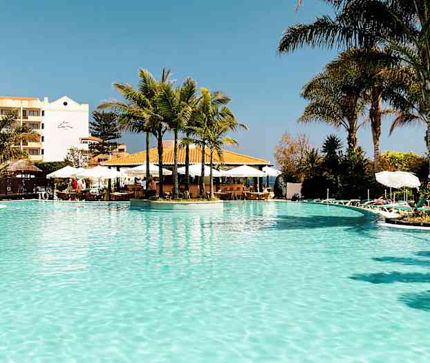 Et utendørs svømmebasseng med palmer og solsenger rundt. (AI-generert tekst)