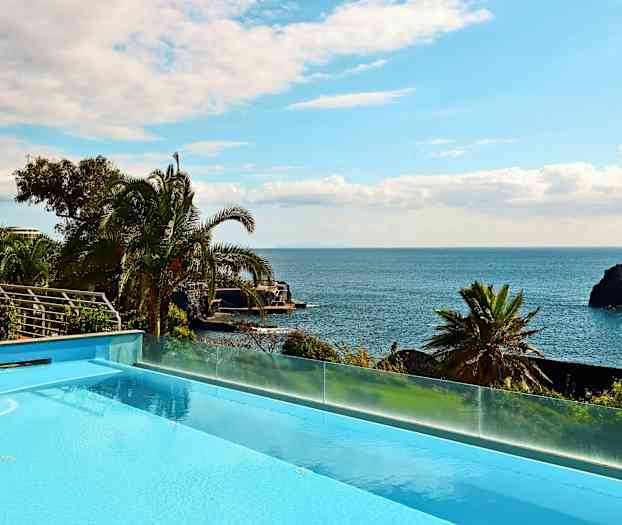 Utsikt over et basseng med havet og palmer i bakgrunnen. (AI-generert tekst)