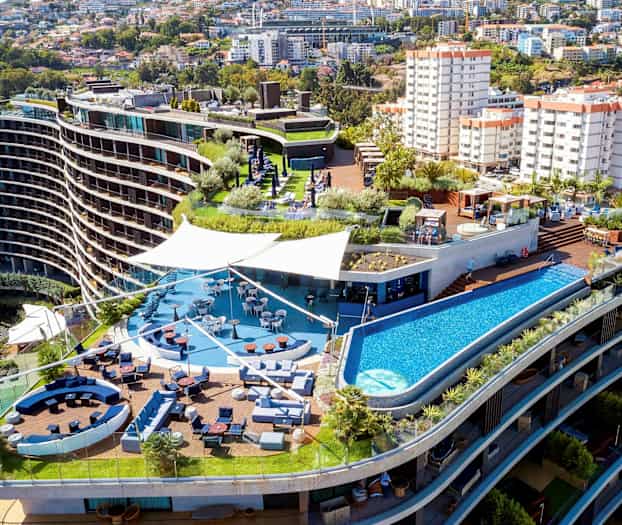 Hotellkompleks med terrasse, basseng og sittegrupper. (AI-generert tekst)