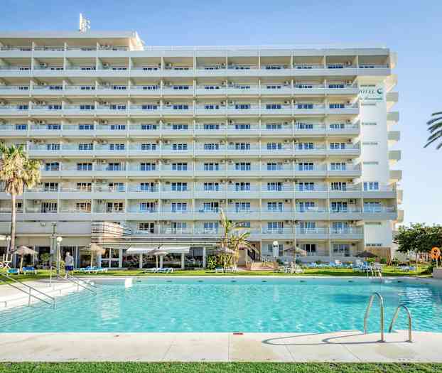 Et leilighetshotell med balkonger foran et svømmebasseng og omkringliggende hage. (AI-generert tekst)