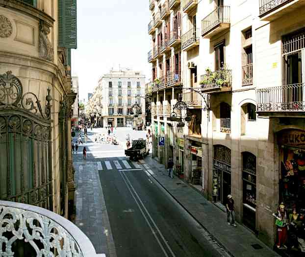 Utsikt over gate med bygninger og mennesker i bymiljø. (AI-generert tekst)
