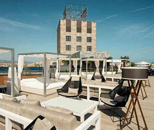 En takterrasse med sittegrupper, solsenger og utsikt over omgivelsene. (AI-generert tekst)