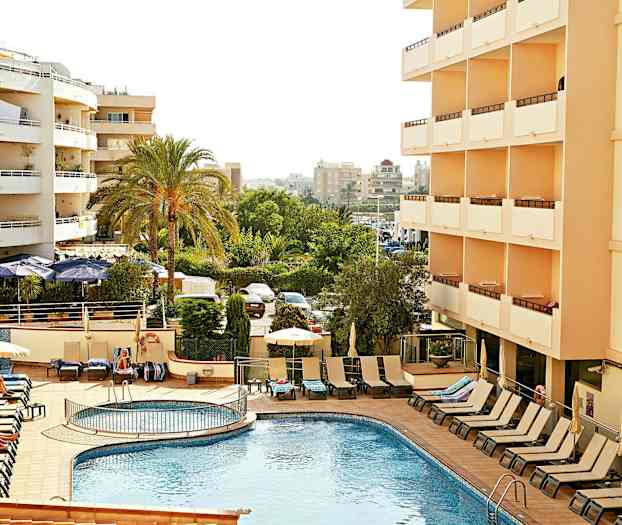 Hotell med utendørsbasseng og solsenger, omgitt av grønne trær og høyblokker. (AI-generert tekst)