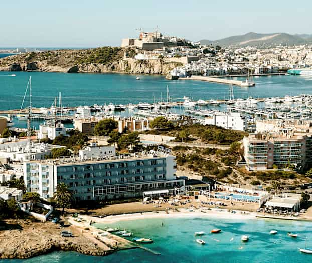 En kystby med flere bygninger og en småbåthavn; små båter og en strand vises i forgrunnen. (AI-generert tekst)