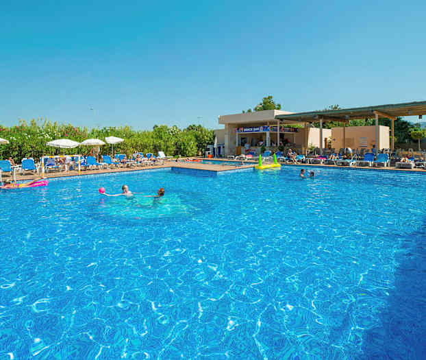 Et utendørsbasseng med klart blått vann omgitt av solsenger og parasoller, med en snackbar i bakgrunnen. (AI-generert tekst)