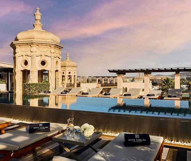 Takbasseng med solsenger og utsikt over byen. Utsmykket arkitektur i bakgrunnen. (AI-generert tekst)