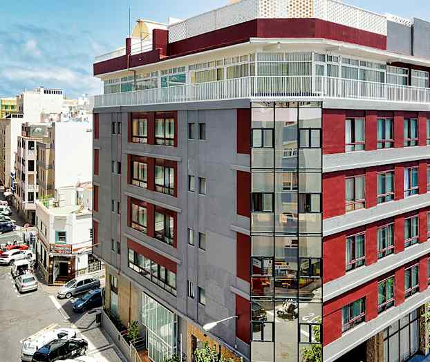 Bilde av en bygning i byen med røde og grå fasader nær sjøen. (AI-generert tekst)