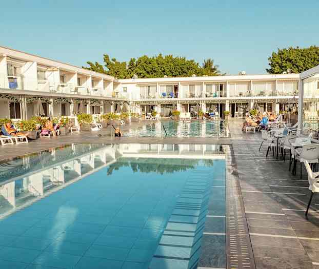 Hotellområde med basseng, solsenger og sitteplasser. (AI-generert tekst)