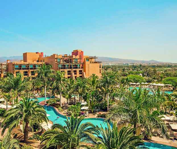 Et feriested med bassenger og omgivelser av palmer, samt bygninger i bakgrunnen. (AI-generert tekst)