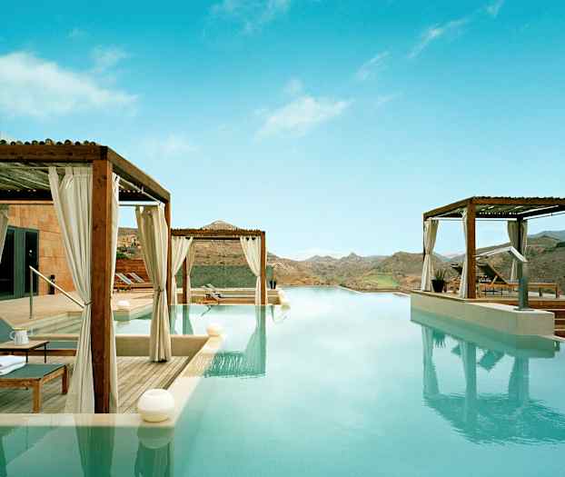 Infinity-basseng med utsikt over fjellandskap og omkringliggende terrasser med solsenger under skjemtak. (AI-generert tekst)