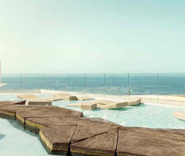 Et infinitybasseng med solsenger og utsikt over havet. (AI-generert tekst)