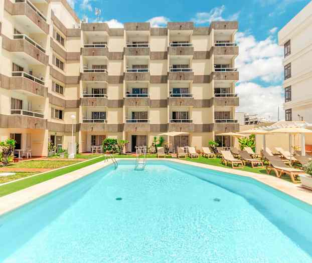 Hotellbygning med basseng foran. (AI-generert tekst)