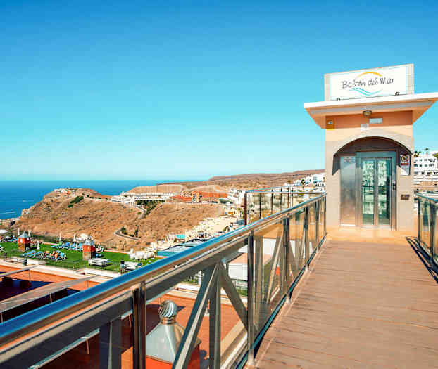 En glassheis ved en gangbro med utsikt over et landskap og havet. (AI-generert tekst)