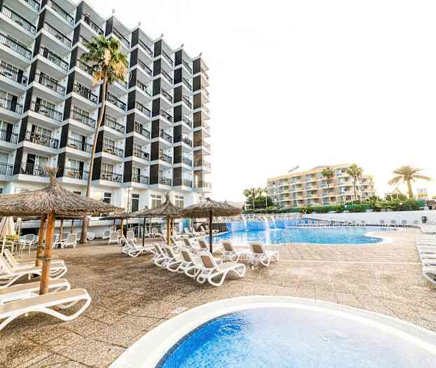 Bilde av et hotellområde med basseng, solsenger og parasoller. (AI-generert tekst)