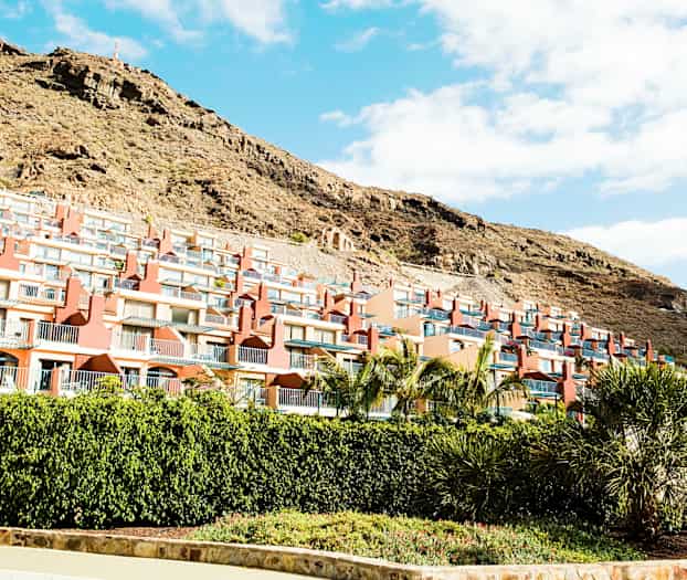 Flere rekkehus med balkonger langs en skråning. (AI-generert tekst)