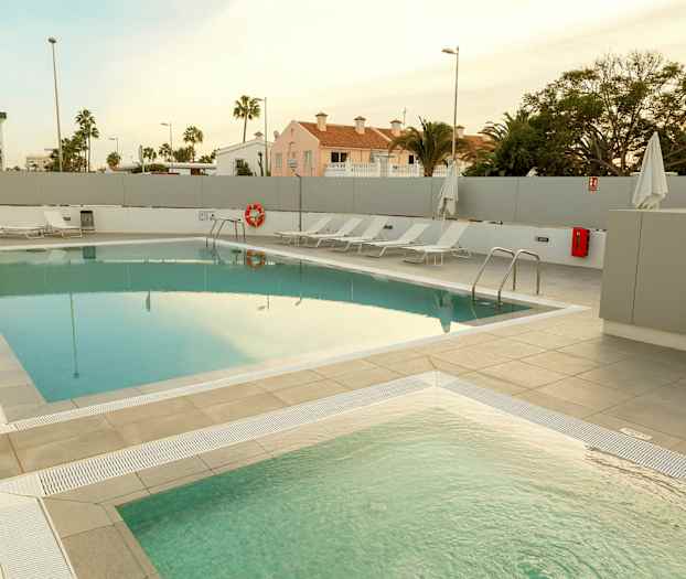 Et utendørs basseng med solsenger ved siden av. (AI-generert tekst)