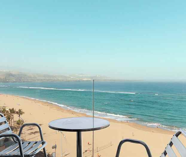 Utsikt fra en balkong mot en sandstrand og havet. (AI-generert tekst)