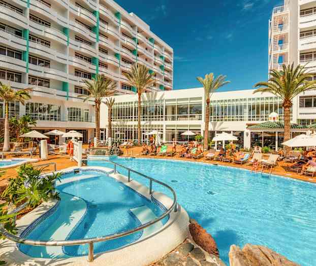 Hotellområde med basseng, solsenger og bygning i bakgrunnen. (AI-generert tekst)