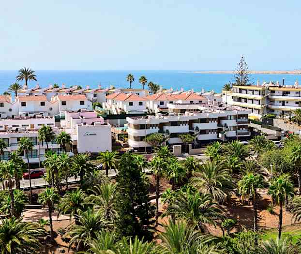 Utsikt over boliger med hager og hav i bakgrunnen. (AI-generert tekst)