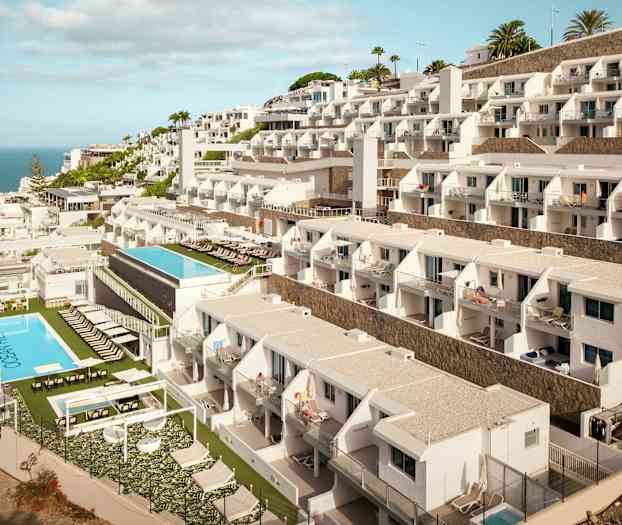 Hotellbygning med flere etasjer og bassenger mot havet. (AI-generert tekst)