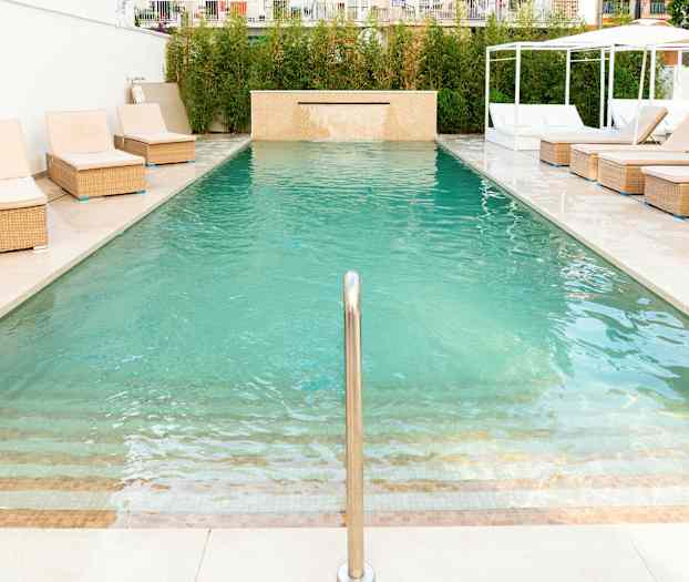 Et svømmebasseng med solsenger ved kanten. (AI-generert tekst)