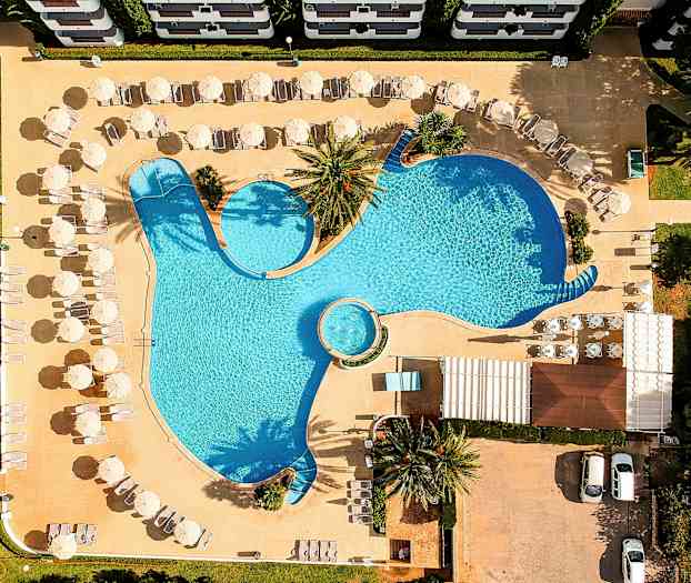 Flyfoto av et basseng med solsenger og parasoller rundt. (AI-generert tekst)