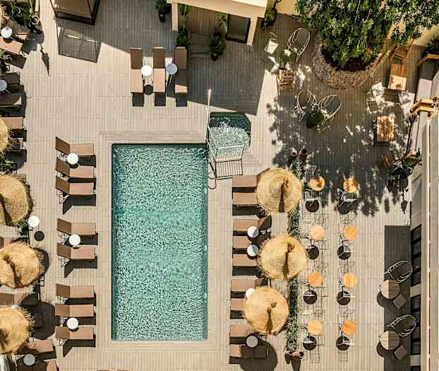 Fugleperspektiv av et basseng omgitt av solsenger, parasoller og bord. (AI-generert tekst)