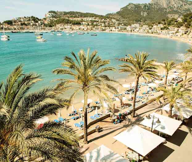 Strand med palmer og solsenger. Vakker utsikt over havet og nærliggende bygninger. (AI-generert tekst)