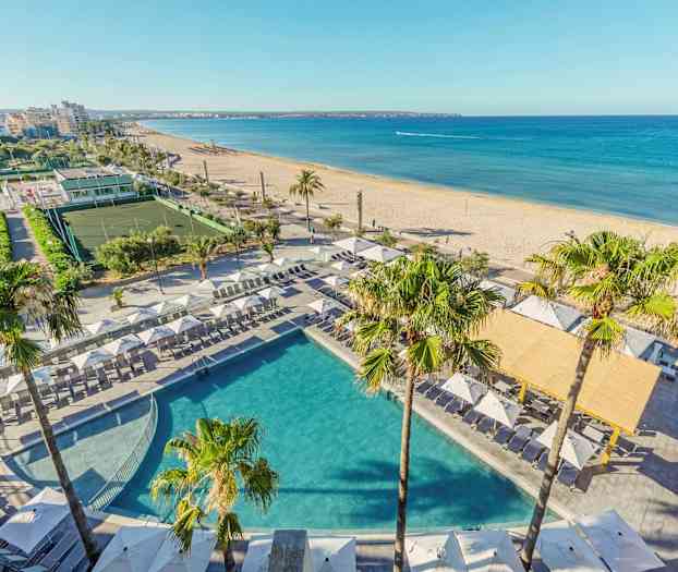 Utsikt over et basseng med solsenger og parasoller ved en strand i et urbant miljø. (AI-generert tekst)