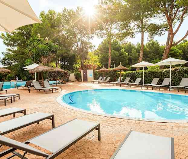 Solstoler ved et basseng med parasoller og trær i bakgrunnen. (AI-generert tekst)