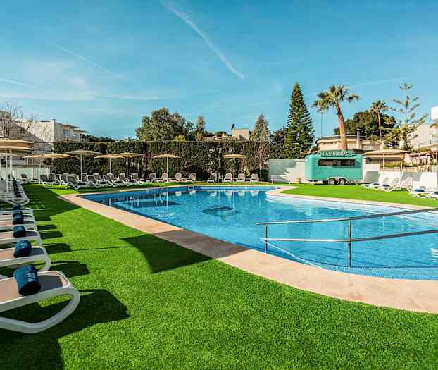 Utendørs basseng med solsenger og grønne omgivelser. (AI-generert tekst)