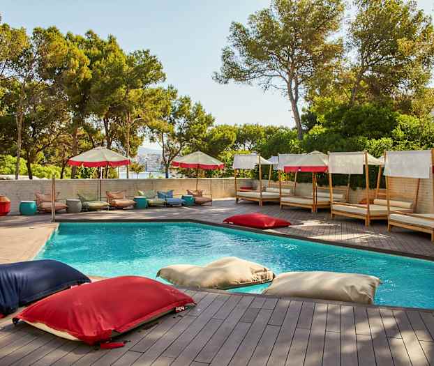 Et utendørsbasseng omgitt av solsenger og parasoller. (AI-generert tekst)