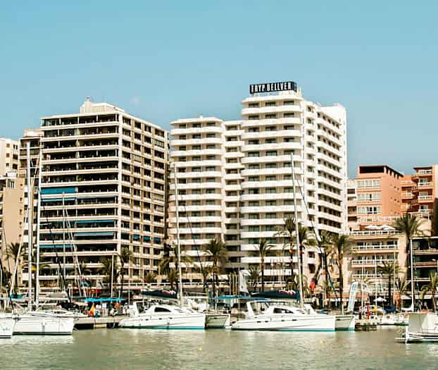 Et bilde av en havn med seilbåter og høye bygninger i bakgrunnen. (AI-generert tekst)