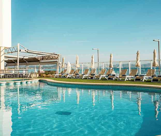 Utendørs svømmebasseng med solsenger og parasoller ved siden av. (AI-generert tekst)